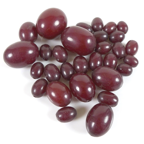 170 - A group of loose cherry amber bakelite beads, largest 22.9mm by 18.6mm, smallest 10mm by 7.6mm, 34.3... 