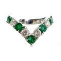 An 18ct white gold, emerald and diamond wishbone ring, set with five circular cut emeralds and three... 