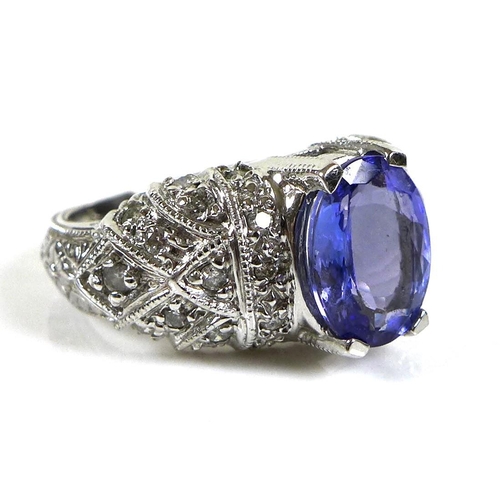 316 - A 14ct white gold and tanzanite dress ring, the single oval stone, 10 by 8mm, set to white gemset sh... 