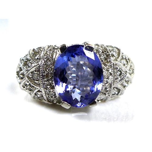 316 - A 14ct white gold and tanzanite dress ring, the single oval stone, 10 by 8mm, set to white gemset sh... 