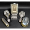 A collection of silver dressing table accoutrements, including a silver photograph frame, stepped co... 