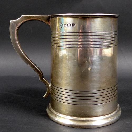 62 - A George V silver 1 pint tankard, with stepped rim and base, scroll handle and two bands of reeded d... 