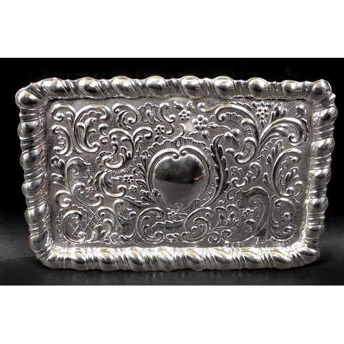 68 - An Edward VII silver dressing table tray, of rectangular form with embossed Rococo style decoration,... 