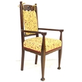 An Arts and Crafts oak open arm chair, with carved back rails, the seat upholstered in yellow, 54 by... 