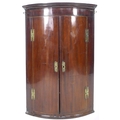 A George III mahogany bow fronted corner cupboard, with green painted interior, 72 by 50 by 106cm hi... 