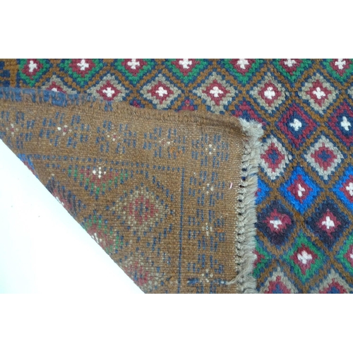 242 - A Baluchi rug with umber ground, diamond patterned field, in red, blue, royal blue, cream and green,... 