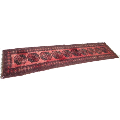 261 - A Tekke rug with red ground, with central row of ten medallions, black decoration, 85 by 372cm.