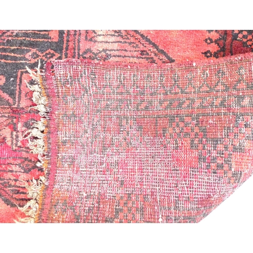 261 - A Tekke rug with red ground, with central row of ten medallions, black decoration, 85 by 372cm.