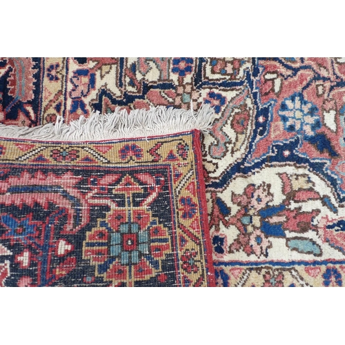 302 - A Heriz carpet with red ground, central cream and dark blue eight petalled medallion, with floral an... 