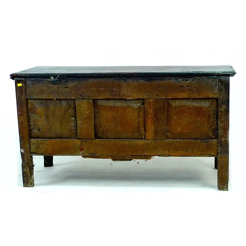 303 - An 18th century oak chest, lift top over a three panel front carved with foliate patterns and lunett... 