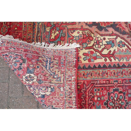 350 - A Heriz carpet with red ground, central cream, grey and red star shaped medallion, dark blue ground ... 