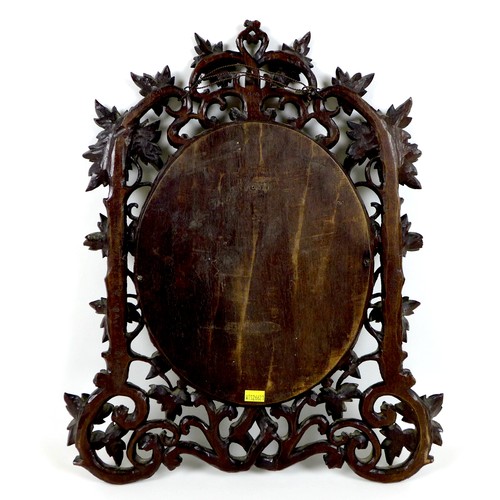 333 - A late 19th century Black Forest carved wall mirror, with oval plate, the framed carved as scrolling... 