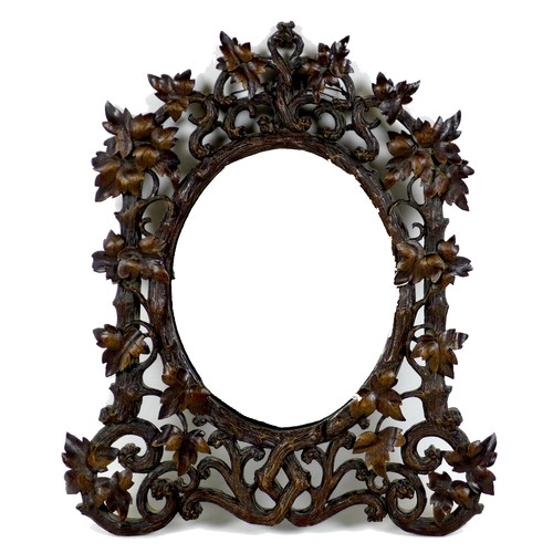 333 - A late 19th century Black Forest carved wall mirror, with oval plate, the framed carved as scrolling... 