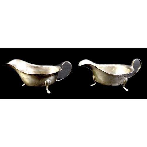 45 - A pair of George V silver sauce boats, of conventional form with shaped rims and three applied feet,... 