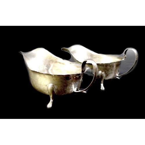 45 - A pair of George V silver sauce boats, of conventional form with shaped rims and three applied feet,... 