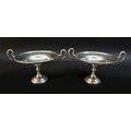 A pair of George V twin handled silver bon bon dishes, raised upon circular stepped bases, both engr... 