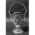 A George V Irish silver pedestal basket dish, with undulating rim and bead border, plain hinged hand... 