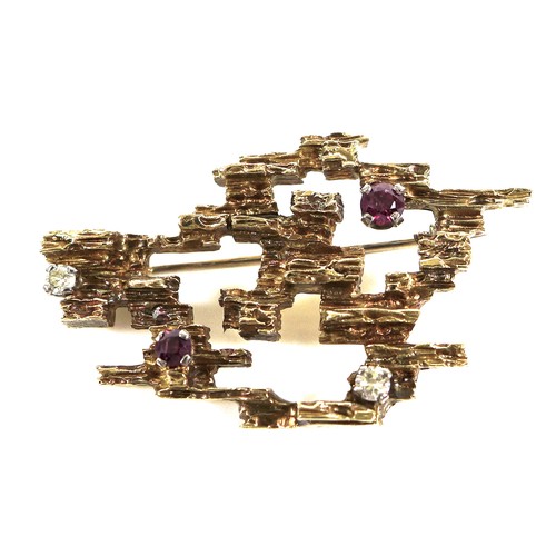 232 - An 18ct gold modernist brooch, pierced cubist form with bark effect finish and inset with two rubies... 