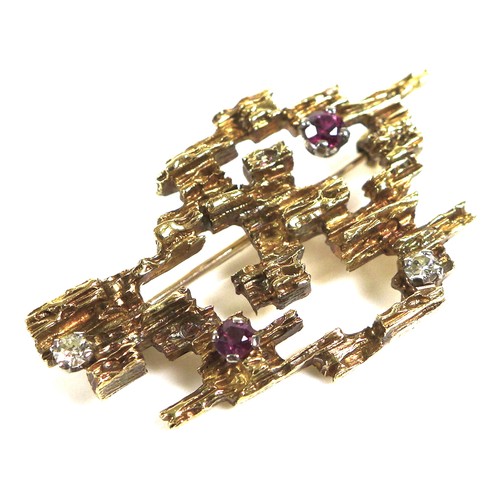 232 - An 18ct gold modernist brooch, pierced cubist form with bark effect finish and inset with two rubies... 