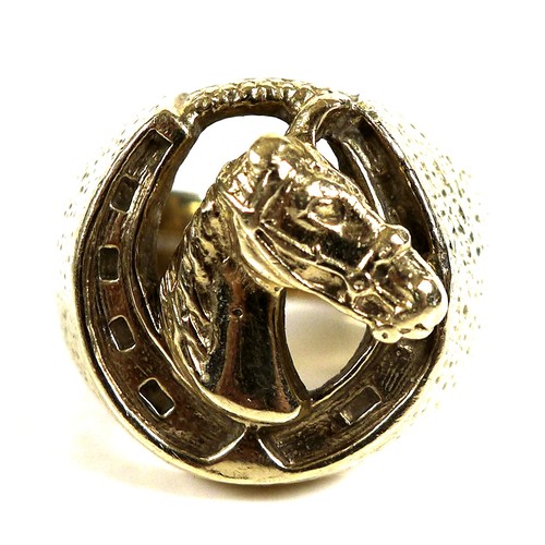 237 - A 9ct gold ring of large textured form, the central motif of a horse within a horseshoe, size Z, 29.... 