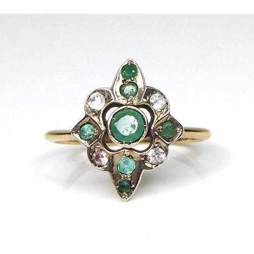 217 - An 18ct gold, emerald and white stone dress ring, the quatrefoil setting with seven emeralds, the ce... 