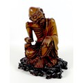 A Chinese carved wooden sculpture, late 19th / early 20th century, modelled as a mendicant, seated b... 