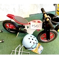 A KiddiMoto children's wooden balance bike, in the form of a red and white trials motorbike, togethe... 
