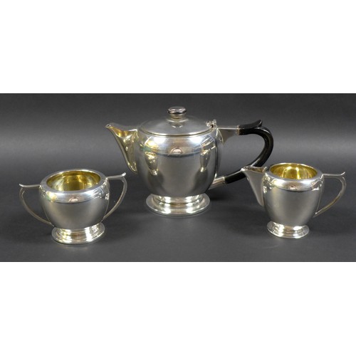 46 - An Art Deco Indian Colonial silver three piece tea set, by Warner Bros, comprising teapot with eboni... 