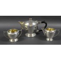 An Art Deco Indian Colonial silver three piece tea set, by Warner Bros, comprising teapot with eboni... 