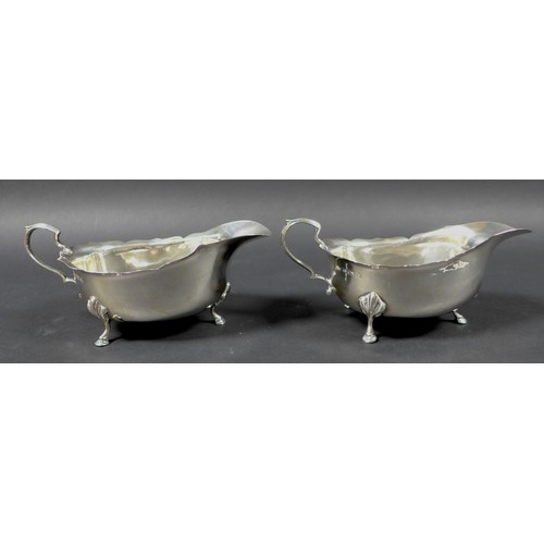 27 - Three Edwardian silver sauce boats, the largest with scroll hand raised upon three claw feet with ac... 