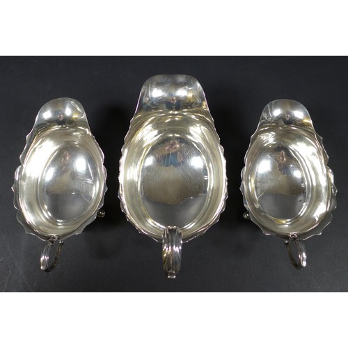 27 - Three Edwardian silver sauce boats, the largest with scroll hand raised upon three claw feet with ac... 