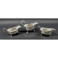 Three Edwardian silver sauce boats, the largest with scroll hand raised upon three claw feet with ac... 