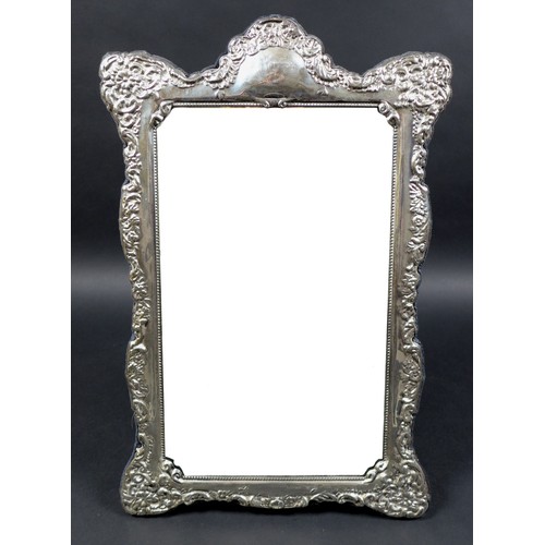 17 - An ERII silver framed mirror on stand, with elaborate foliate and scroll decorative border design, C... 