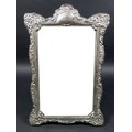 An ERII silver framed mirror on stand, with elaborate foliate and scroll decorative border design, C... 