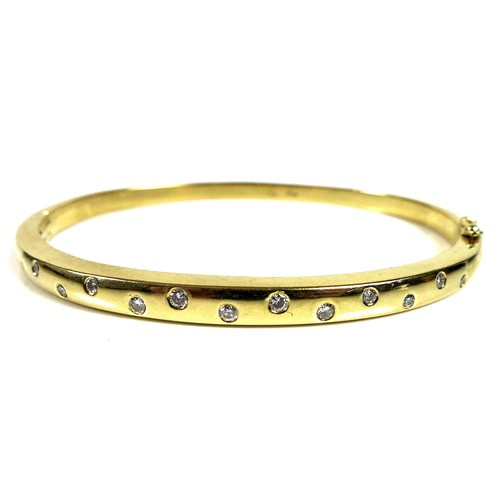 372 - An 18ct gold and diamond bangle, set with thirteen graduated brilliant cut stones, hinge clasp, 6cm ... 