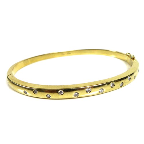 372 - An 18ct gold and diamond bangle, set with thirteen graduated brilliant cut stones, hinge clasp, 6cm ... 