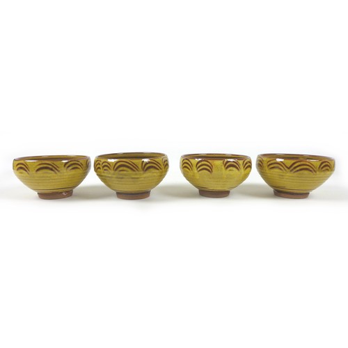 18 - Clive Bowen (British, b. 1943): a set of four Studio pottery bowls, yellow and brown slip glaze, eac... 