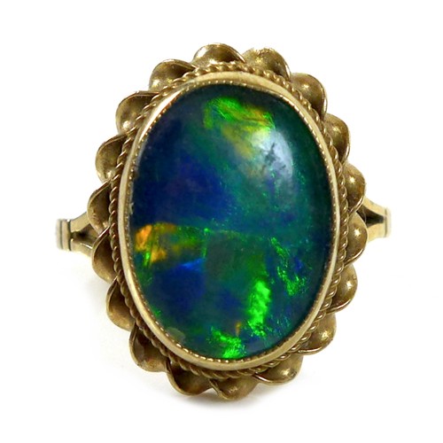 110 - A 9ct gold and blue opal ring, the central stone of approximately 1.9 by 1.5cm within a rope twist s... 