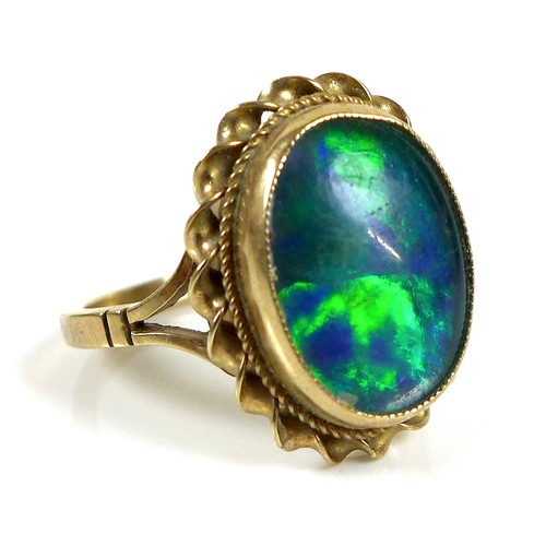 110 - A 9ct gold and blue opal ring, the central stone of approximately 1.9 by 1.5cm within a rope twist s... 