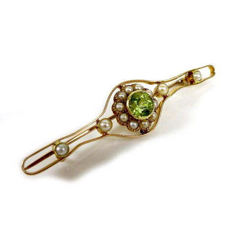 118 - A 15ct gold, peridot and pearl open bar brooch, the central stone of 0.5cm diameter and surrounded b... 