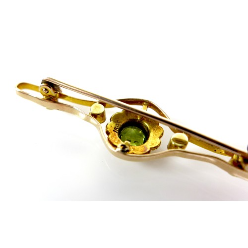 118 - A 15ct gold, peridot and pearl open bar brooch, the central stone of 0.5cm diameter and surrounded b... 