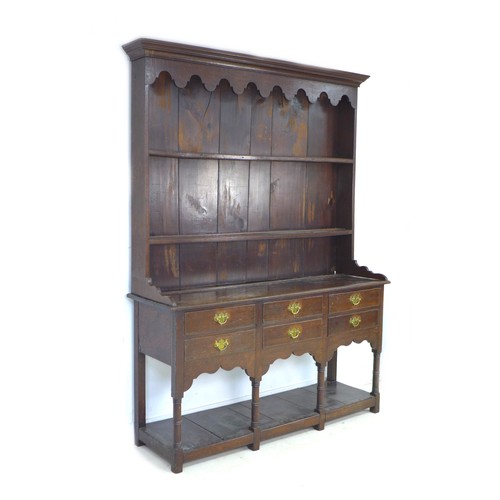 233 - A Georgian oak dresser, with shaped cornice and  closed back top with two plate rack shelves, its ba... 