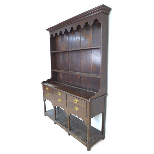 233 - A Georgian oak dresser, with shaped cornice and  closed back top with two plate rack shelves, its ba... 