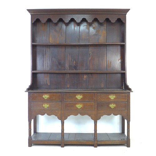 233 - A Georgian oak dresser, with shaped cornice and  closed back top with two plate rack shelves, its ba... 