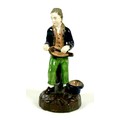 A late 18th century porcelain figure, possibly Derby, modelled as a man playing a hurdy-gurdy, weari... 