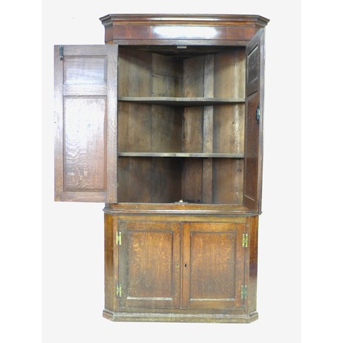 238 - A George III oak and mahogany corner cupboard, floor-standing, with panelled doors and shelved inter... 