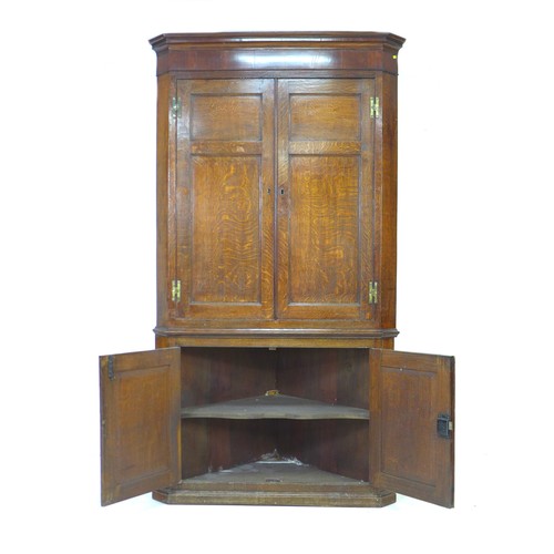 238 - A George III oak and mahogany corner cupboard, floor-standing, with panelled doors and shelved inter... 