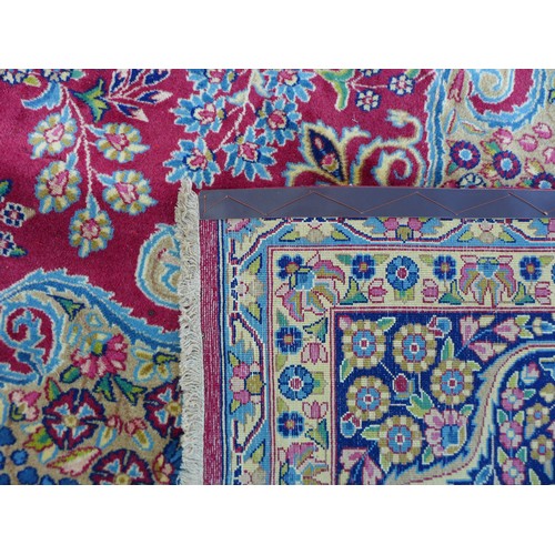 234 - A Kerman carpet on red ground, with central medallion surrounded with scrolling floral and foliate d... 