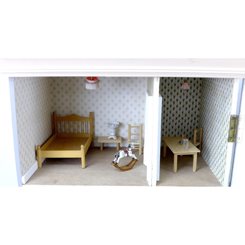 130 - A mid 20th century dolls house, with a single hinged door concealing a three storey interior, togeth... 