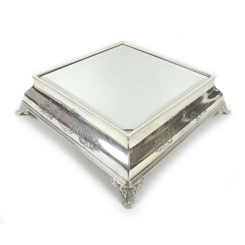 157 - An early 20th century silver plated wedding cake stand, of square form with bevelled mirror surface,... 